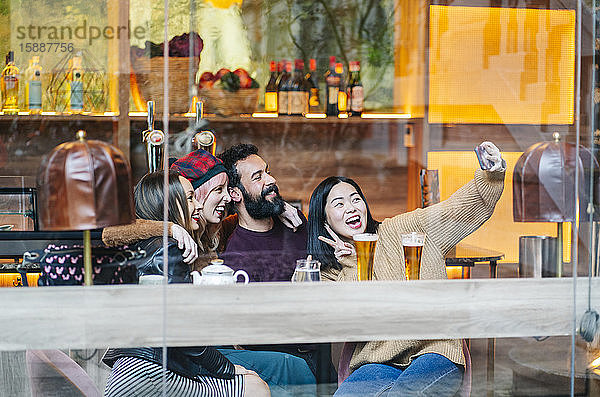 Freunde treffen sich in einer angesagten Bar und nehmen sich selbst ein Smartphone