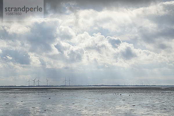 Deutschland  Schleswig-Holstein  Dramatische Wolken über Wattenmeer-Nationalparks mit Windkraftanlagen im fernen Hintergrund