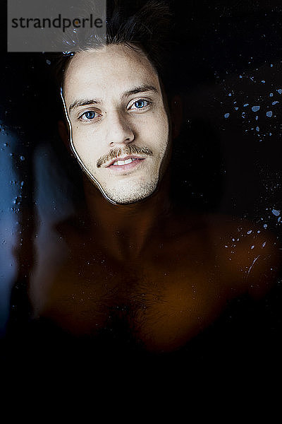 Porträt eines jungen Mannes mit blauen Augen im Wasser