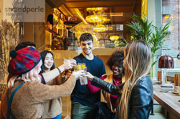 Freunde treffen sich in einer trendigen Bar  anstoßend