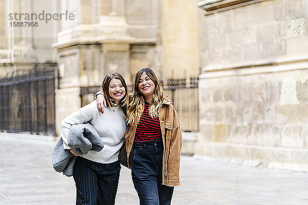 Zwei glückliche junge Frauen gehen in der Stadt spazieren