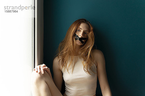 Porträt einer jungen Frau mit zugeklebtem Mund
