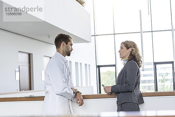Geschäftsfrau und Arzt sprechen im Krankenhaus