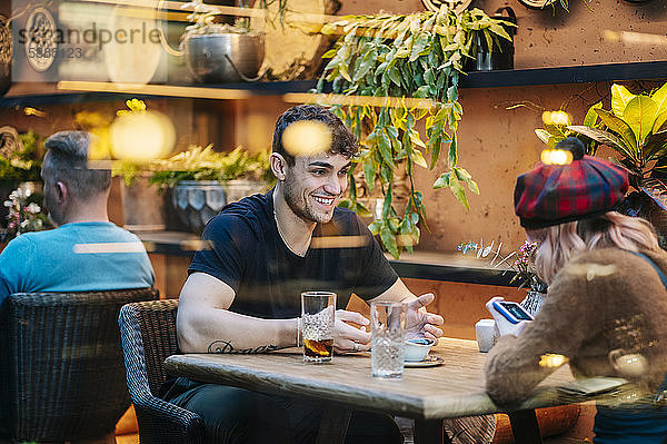 Mann und Frau trinken in einem Restaurant  unterhalten sich  benutzen ein Smartphone