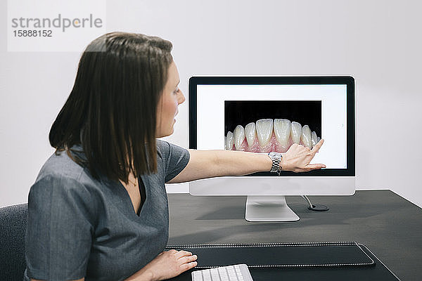 Zahnarzt zeigt auf dem Bildschirm im Büro auf das Alter der Zähne