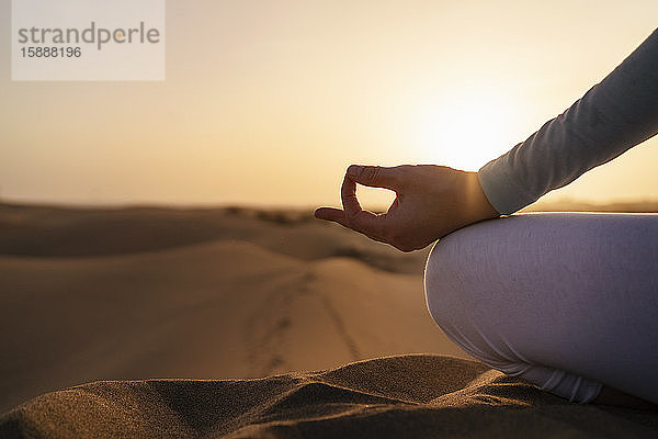 Nahaufnahme einer Frau  die bei Sonnenuntergang in Sanddünen Yoga praktiziert  Gran Canaria  Spanien