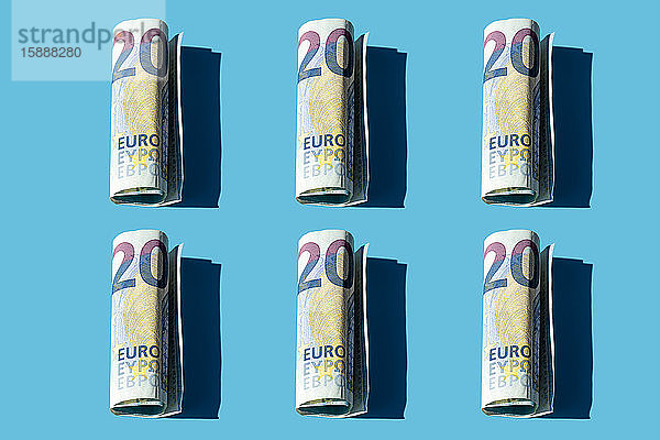 Muster von zwanzig gerollten Euro-Banknoten auf blauem Hintergrund