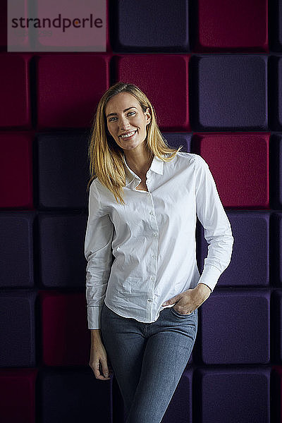 Porträt einer lächelnden Frau an einer violetten Wand