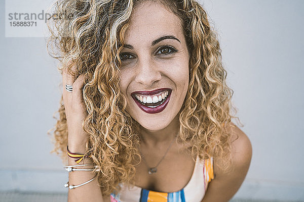 Porträt einer glücklichen jungen Frau mit blonden Locken