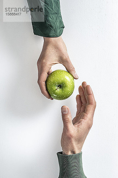 Draufsicht einer Frau  die einem Mann einen grünen Apfel überreicht