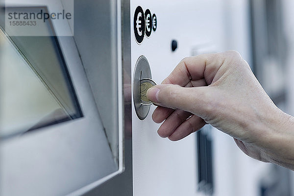Hand einer Frau  die Münzen in den Münzautomat einwirft