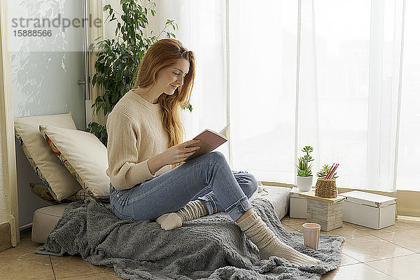 Junge Frau liest zu Hause ein Notizbuch