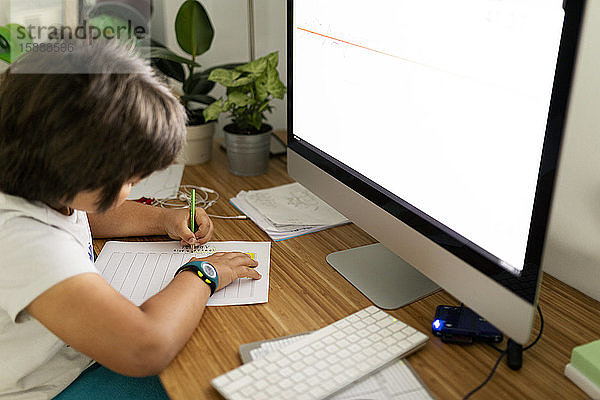 Junge sitzt zu Hause am Schreibtisch und malt Zeitplan