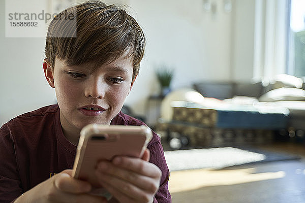 Porträt eines Jungen  der zu Hause ein Smartphone benutzt