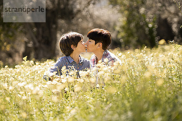 Mutter und Tochter küssen sich auf einem Feld mit Wildblumen