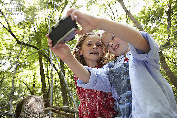 Mädchen  die mit einer Retro-Kamera Selbstporträts im Wald machen