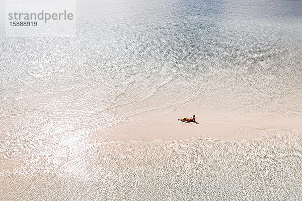 Sonnenbad einer Frau auf weißer Sandbank im Meer  Bahamas  Karibik