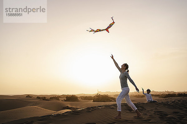 Mutter und Tochter fliegen Drachen in Sanddünen bei Sonnenuntergang  Gran Canaria  Spanien