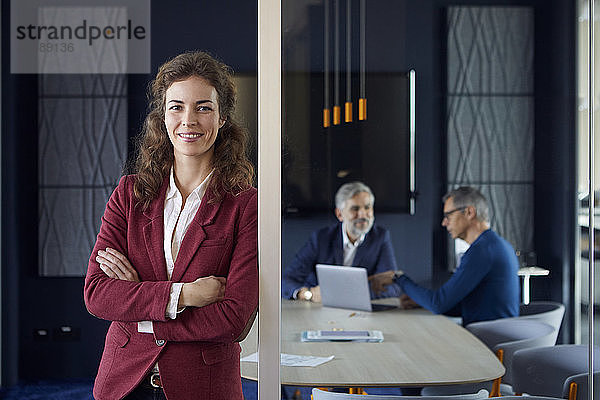 Porträt einer selbstbewussten Geschäftsfrau im Amt mit Kollegen im Hintergrund