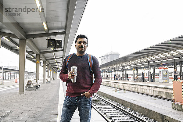 Porträt eines Mannes mit wiederverwendbarem Becher am Bahnhof