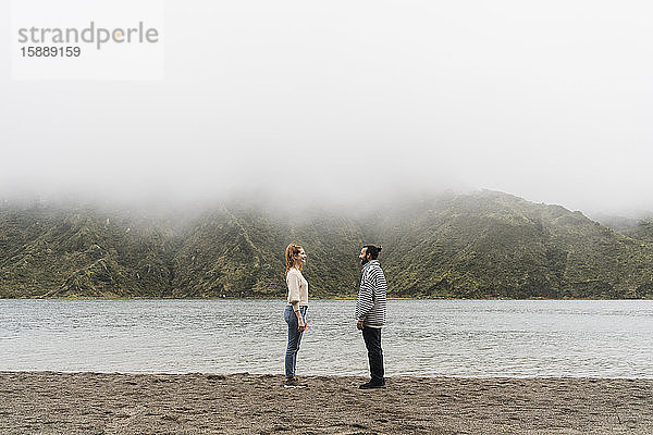 Glückliches Paar steht sich am Seeufer auf der Insel Sao Miguel  Azoren  Portugal  gegenüber