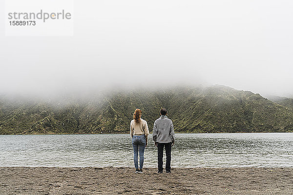 Rückansicht eines Paares am Seeufer bei der gemeinsamen Erkundung der Insel Sao Miguel auf den Azoren  Portugal