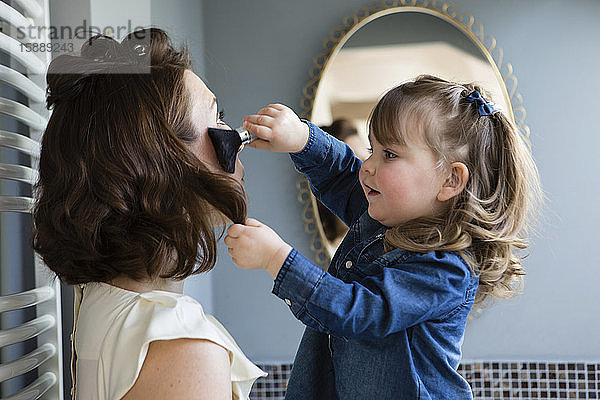 Kleinkind Mädchen schminkt das Gesicht ihrer Mutter