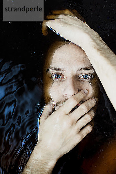 Porträt eines jungen Mannes mit blauen Augen im Wasser