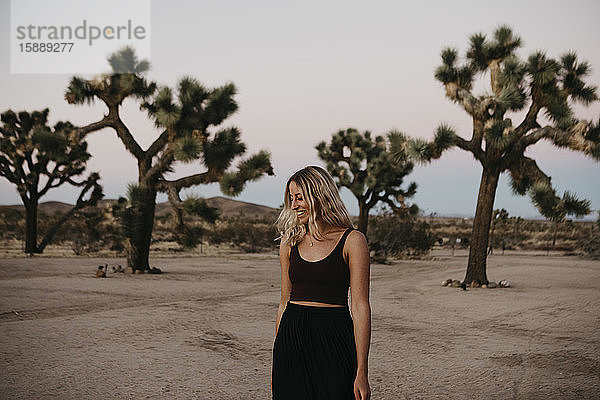 Lächelnde blonde Frau beim Spaziergang in der Wüste in der Dämmerung  Joshua Tree  USA Joshua Tree  USA