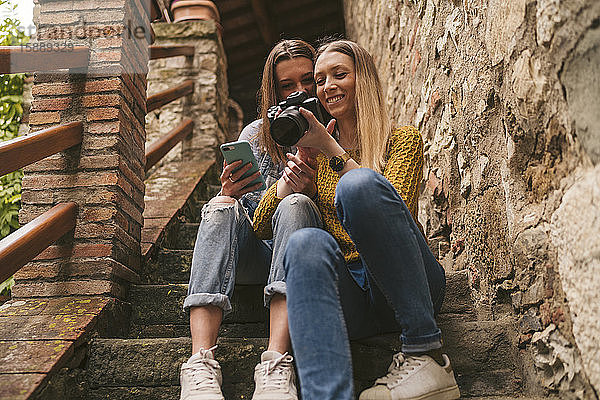 Zwei junge Frauen sitzen auf einer Treppe und schauen in die Kamera  Greve in Chianti  Toskana  Italien