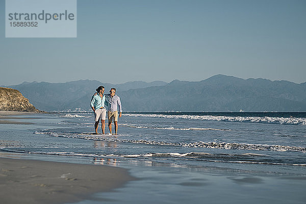 Reife schwule Männer halten sich bei Strandspaziergängen am Strand vor klarem blauen Himmel an den Händen  Riviera Nayarit  Mexiko