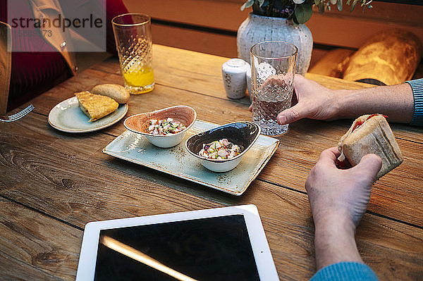 Zwei Personen sitzen im Restaurant  essen und trinken  mit digitalem Tablett auf dem Tisch