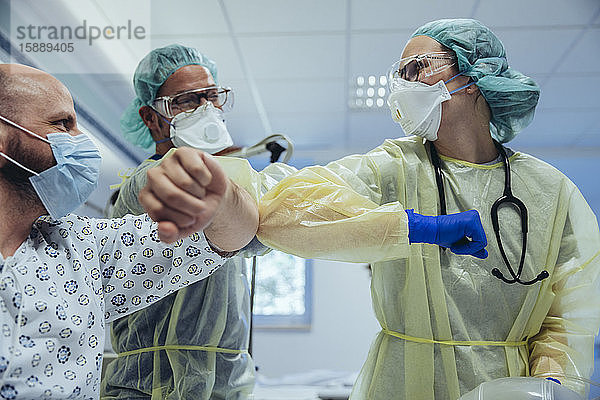 Ärzte machen Ellbogenstoß mit geheiltem Patienten auf der Notfallstation eines Krankenhauses