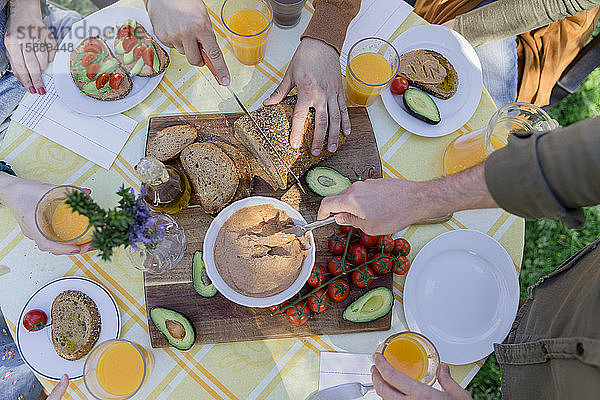 Nahaufnahme von Freunden  die ein gesundes veganes Frühstück im Freien genießen
