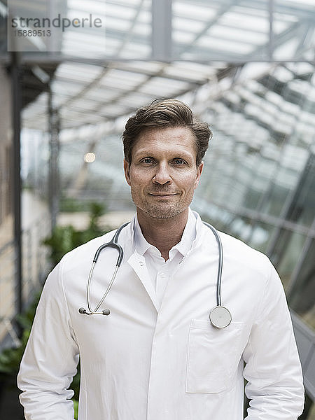 Porträt eines Arztes mit Stethoskop  stehend im Atrium
