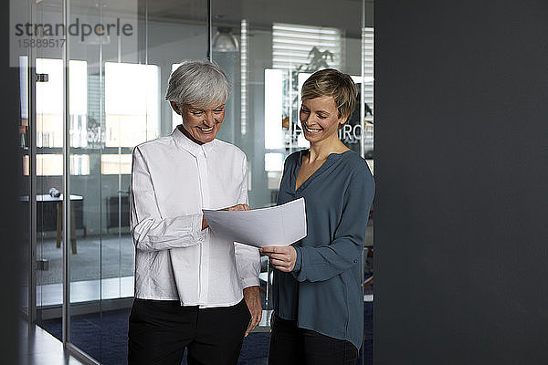 Zwei Geschäftsfrauen arbeiten zusammen auf Papier im Amt