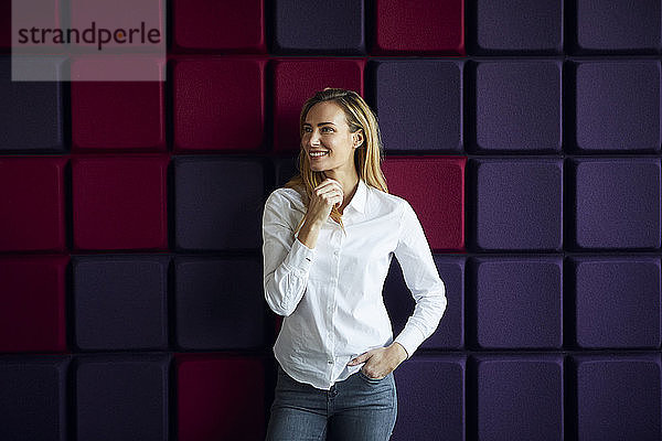Porträt einer lächelnden Frau an einer violetten Wand