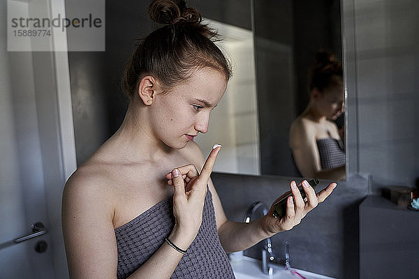 Mädchen benutzt Gesichtscreme im Badezimmer