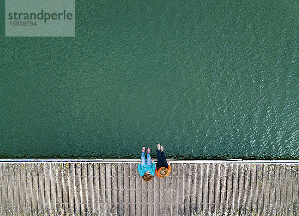 Zwei Freunde sitzen nebeneinander auf dem Bootssteg  Stausee Valdemurio  Asturien  Spanien