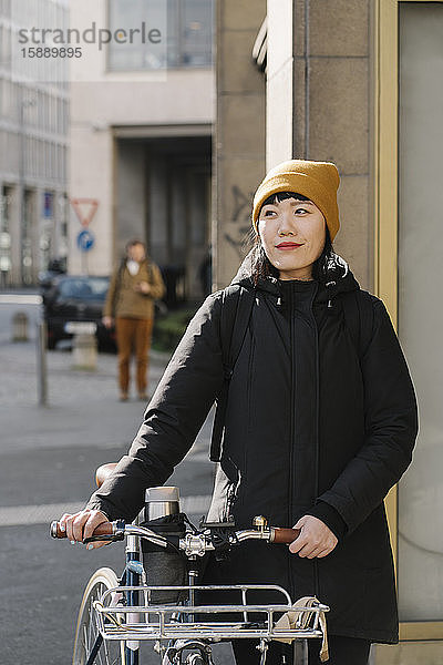 Porträt einer selbstbewussten Frau mit Fahrrad in der Stadt  Frankfurt  Deutschland