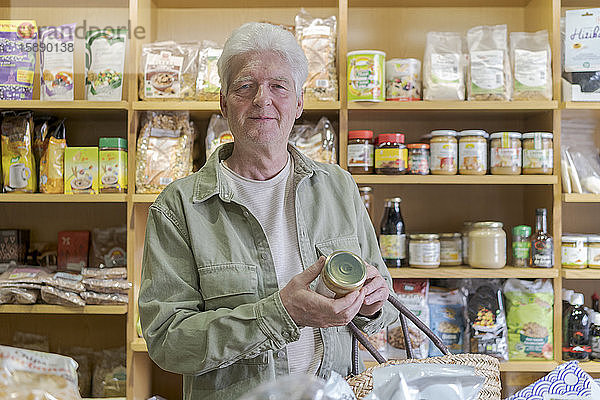 Porträt eines älteren Mannes beim Einkaufen von Lebensmitteln in einem kleinen Lebensmittelgeschäft