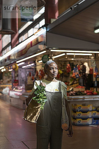 Frau kauft Lebensmittel in einer Markthalle