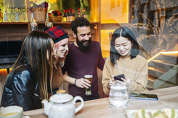 Freunde treffen sich in einer angesagten Bar mit Blick auf das Smartphone