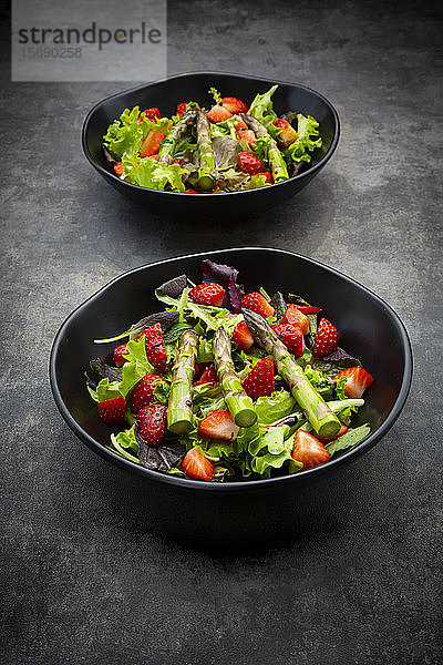 Zwei Schalen mit vegetarischem Salat mit Salat  Erdbeeren und Spargel