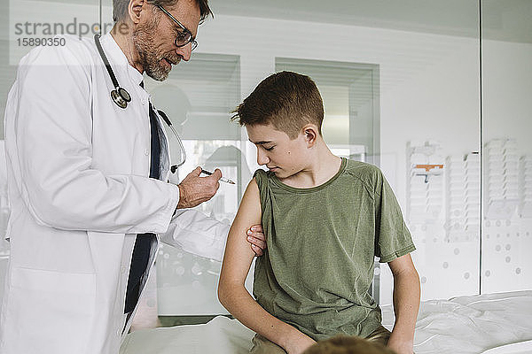 Arzt injiziert Impfstoff in den Arm eines Teenagers
