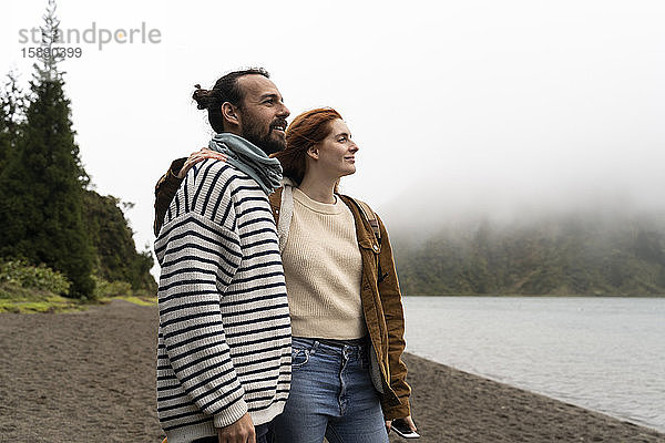 Ein lächelndes Paar betrachtet einen malerischen See  während es Urlaub auf der Insel Sao Miguel  Azoren  Portugal  macht