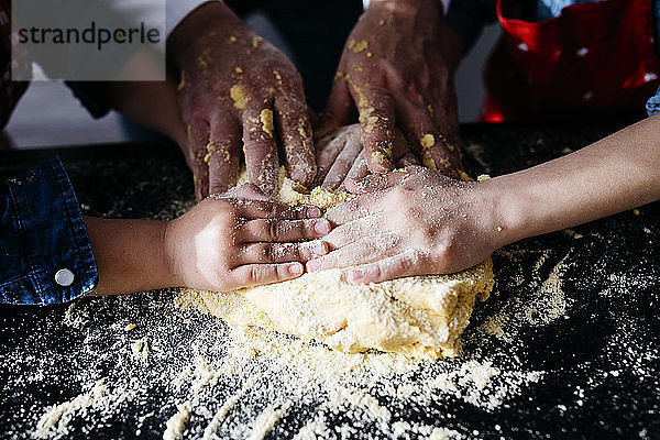 Nahaufnahme der Hände bei der Zubereitung von Teig in der heimischen Küche
