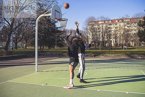Junger Mann und Frau spielen Basketball auf dem Platz