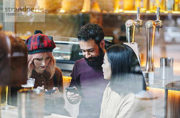 Freunde treffen sich im Restaurant  unterhalten sich  schauen auf Smartphones