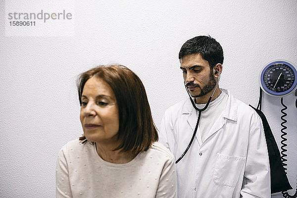 Arzt untersucht Patient mit einem Stethoskop in der medizinischen Praxis